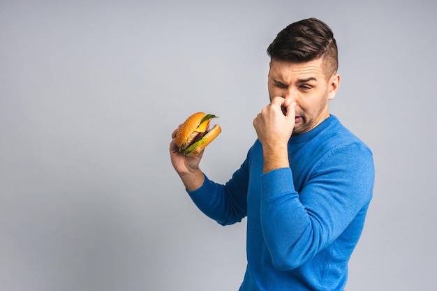 Un apuesto joven ucraniano rechazando una hamburguesa malsana aislada sobre un fondo gris blanco Concepto de dieta con espacio para copiar texto