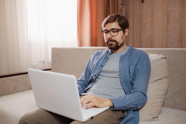 Apuesto joven usando computadora portátil en casa