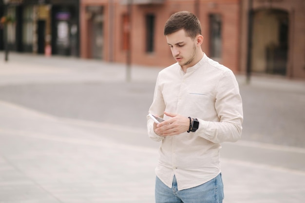 Apuesto joven usando su teléfono en el centro de la ciudad Hombre llamando a su novia