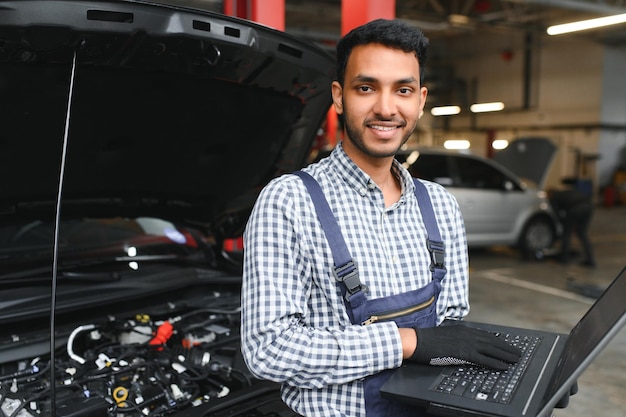 Foto apuesto mecánico de automóviles indio en el servicio de automóviles