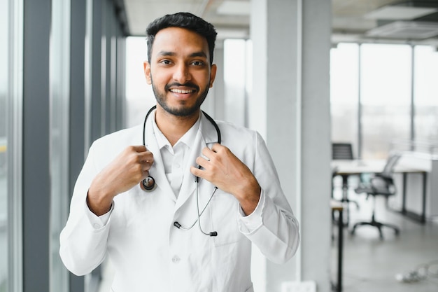 Apuesto médico indio sosteniendo un frasco cuentagotas blanco o en blanco vacío