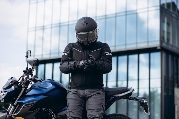 Foto apuesto motociclista en su moto montando en la ciudad