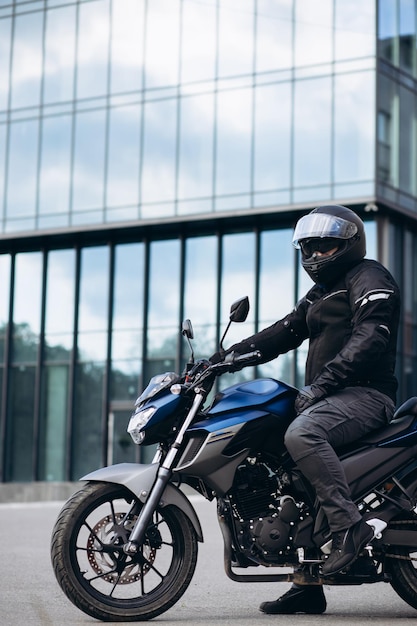 Apuesto motociclista en su moto montando en la ciudad