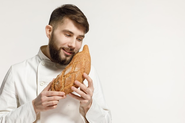 Un apuesto panadero en uniforme sostiene baguettes en un concepto de publicidad de panadería de fondo blanco