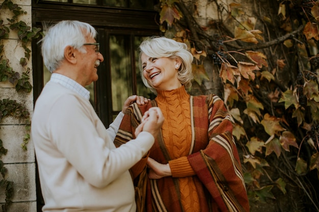 Apuesto pareja senior abrazándose en el parque otoño