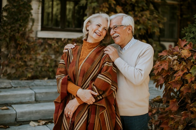 Apuesto pareja senior abrazándose en el parque otoño