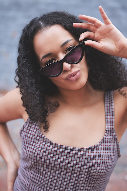 Foto apuesto a que piensas que soy genial foto de una mujer joven con gafas de sol mientras posa afuera