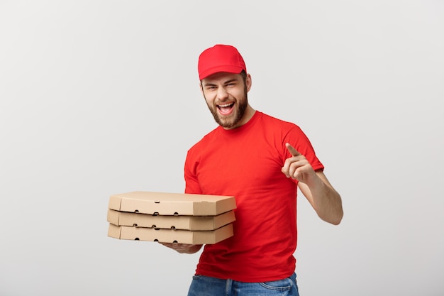 Apuesto repartidor de pizza mensajero en uniforme rojo con tapa con cajas de pizza.