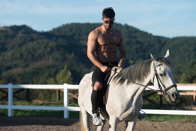Apuesto vaquero macho montando a caballo Fondo de cielo y montañas