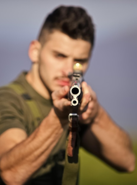 Foto apuntado cañón de pistola enfoque selectivo hombre musculoso sostener arma propósito y éxito polígono ejercicios de combate estilo militar fuerzas del ejército francotirador alcanzar objetivo hombre listo para disparar cazador hobby