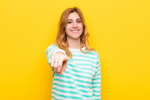 apuntando a la cámara con una sonrisa satisfecha, segura y amigable, eligiéndote