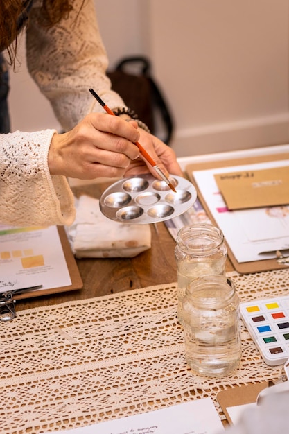 Aquarell-Workshop Die Hand einer Frau, die Farben mit Wasserfarben mischt