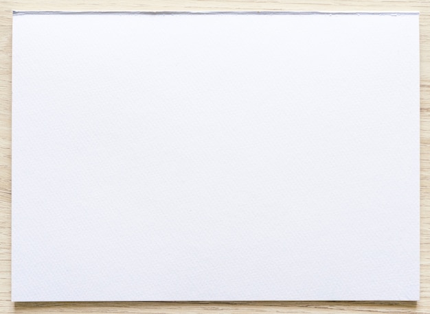 Foto aquarellpapierbeschaffenheit auf hölzernem hintergrund mit beschneidungspfad. weißes papierblatt mit zerrissenen kanten. kunstdruckpapier hochwertige textur in einer hohen auflösung.