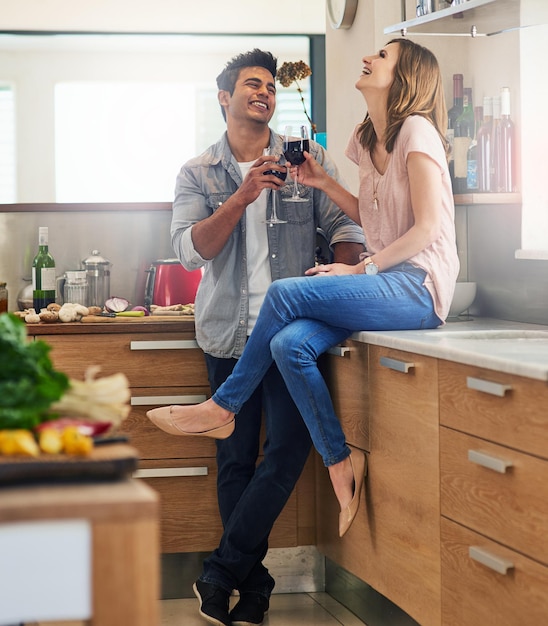 Aqui está o amor Foto de um jovem casal afetuoso bebendo vinho na cozinha