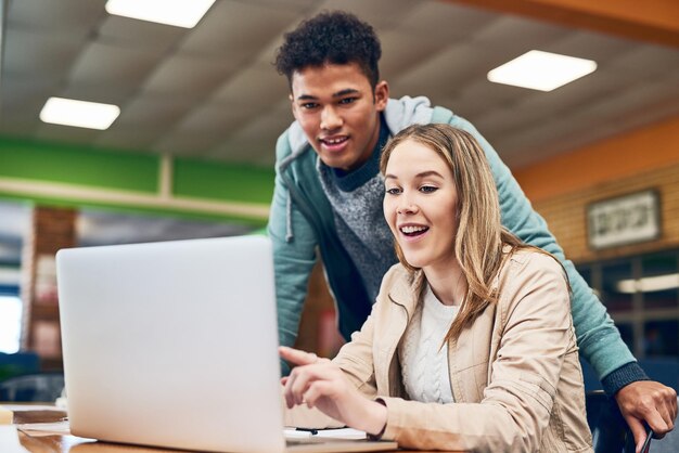 Aquí está toda la información al alcance de la mano Foto de un joven mirando mientras una estudiante trabaja en una computadora portátil