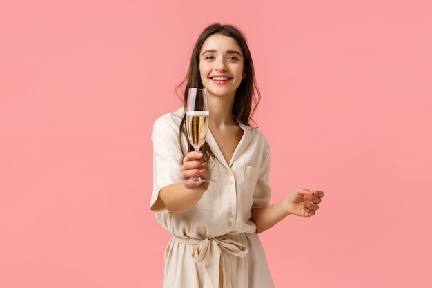 Aqui, faça um brinde. Alegre namorada jovem romântica e sedutora, estendendo a mão com vidro, dando champanhe para o namorado, sorrindo alegremente, curtindo a festa incrível, rosa