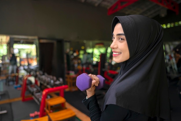 Arab middle eastern muslim woman working out while lifting a dumbbell at the gym Fitness exercise and healthy lifestyle concept