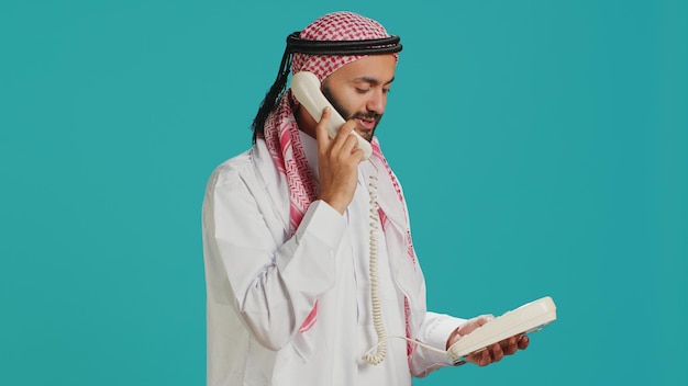 Foto un árabe habla por teléfono fijo.