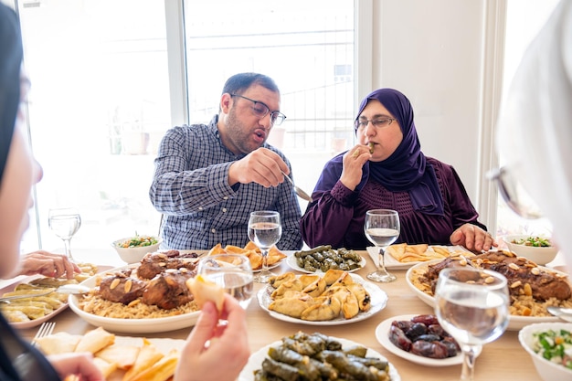 Arabische Familie, die zusammen an einem Holztisch mit Vater, Mutter, Großvater, Großmutter und Sohn essen