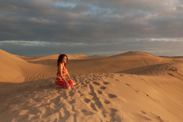 Arabische Frau tanzt Bauchtanz in den Wüstendünen bei Sonnenuntergang