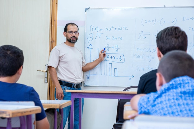 Arabische Kinder in der Schule sind so aufgeregt mit ihrem Lehrer und heben die Hände, um die Fragen des Lehrers zu beantworten