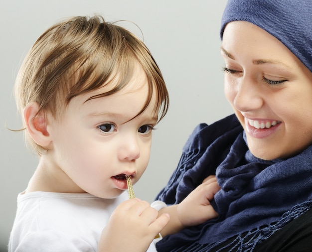 Arabische moslemische Mutter, die um ihrem Baby spielt und sich kümmert