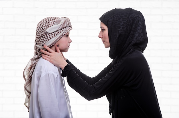 Arabische Mutter und Sohn posieren drinnen.