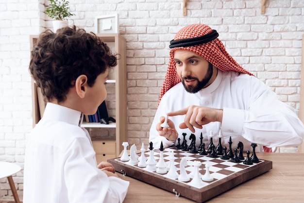 Arabischer bärtiger Vater und kleiner Sohn spielen Schach.