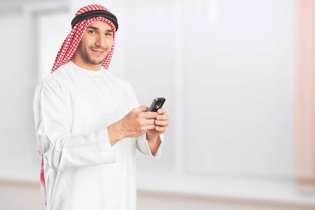 Arabischer Geschäftsmann blickt auf sein Mobiltelefon und lächelt