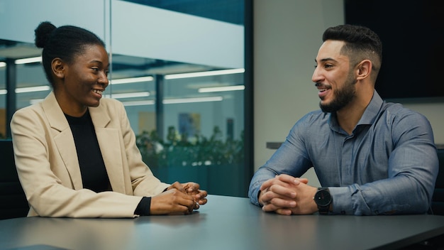 Arabischer indischer Geschäftsmann und afroamerikanische Geschäftsfrau sprechen im Büro über ein Projekt