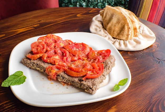 Arabischer kebab würzig mit tomate oben auf türkisch auf dem holzhintergrund