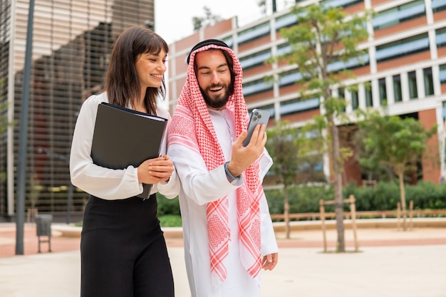 Arabischer Mann, der Geschäftsfrau Handy zeigt