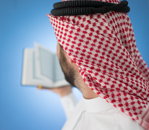 Arabischer Mann, der mit Koran betet