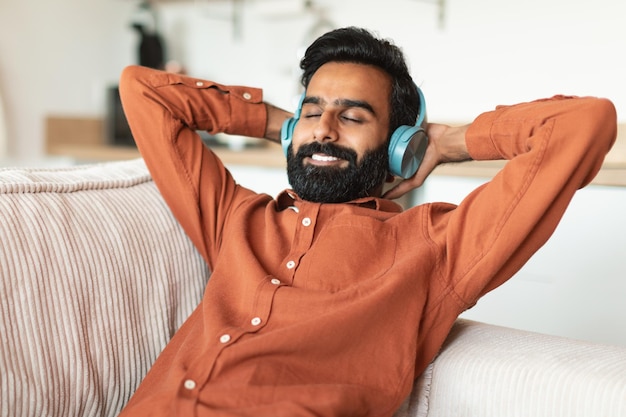 Arabischer Mann genießt zu Hause Lieder und Musik in Kopfhörern