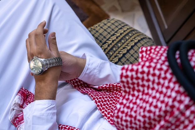 Arabischer Mann mit Dishdasha und Blick auf seine Armbanduhr