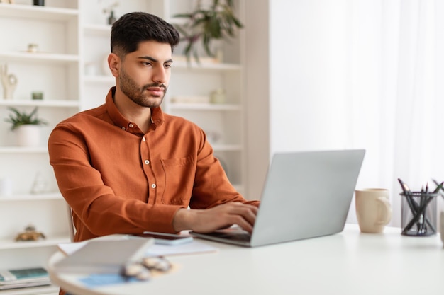 Arabischer Mann mit Laptop am Schreibtisch im Büro