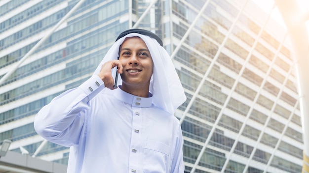 Arabischer Mann steht und benutzt Handy Stadtplatz am im Freien am Morgen