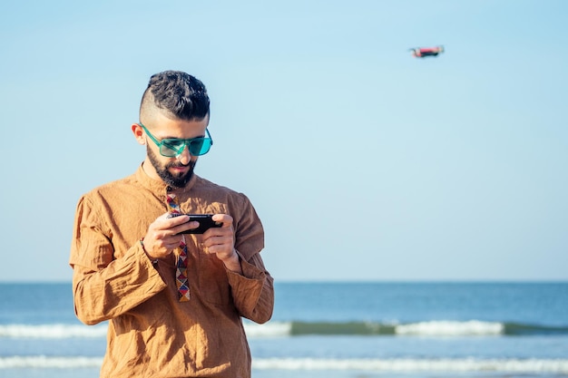 Arabischer Mann testet ein Drohnen-Foto- und Video-Shooting mit einem Quadrocopter über dem Meer am Strand von Goa