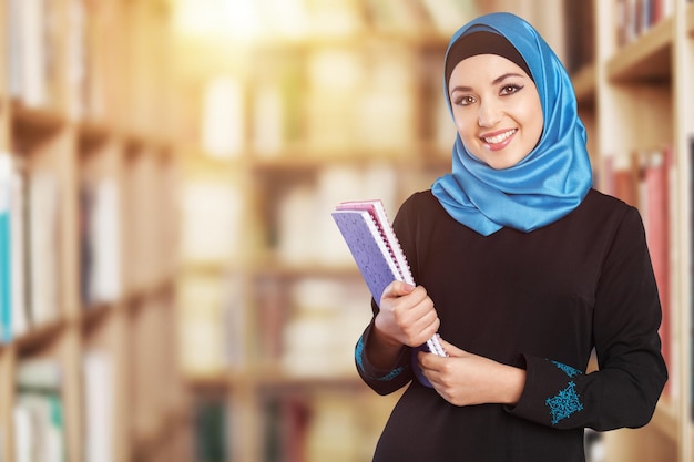 Arabischer Student, der im Bibliothekshintergrund steht