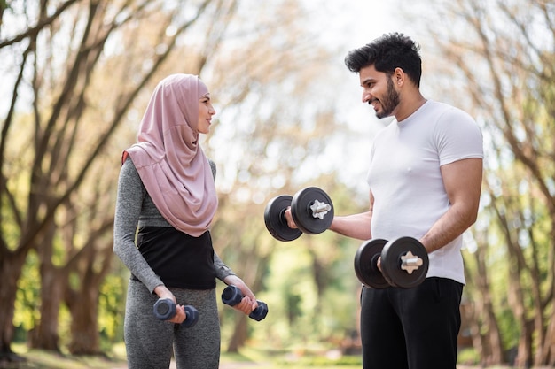 Arabisches Paar mit Hanteln während des Trainings im Park