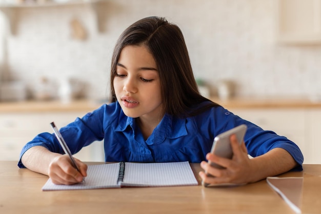 Arabisches Schulmädchen hat Online-Unterricht per Telefon und macht sich drinnen Notizen