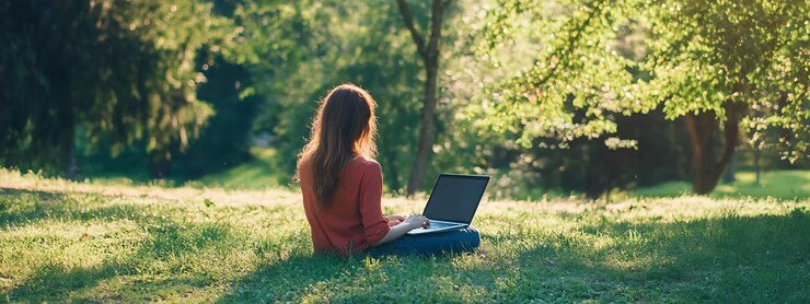 araffe sentado en la hierba con una computadora portátil en su regazo