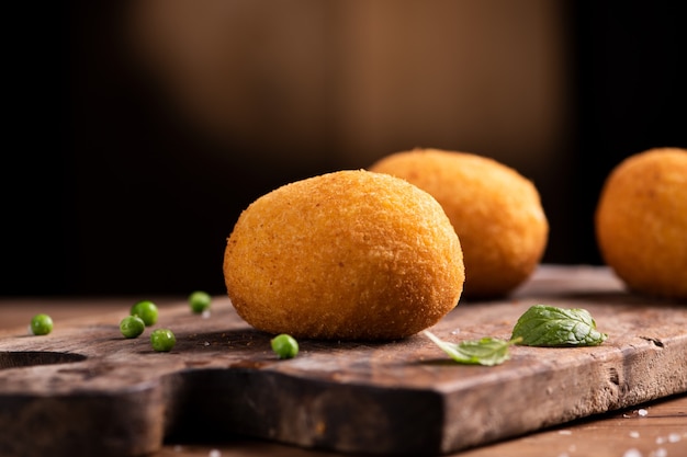 Arancini-Reisbällchen. Gebratene Reisbällchen auf braunem Holzhintergrund. Snack, Streetfood hautnah