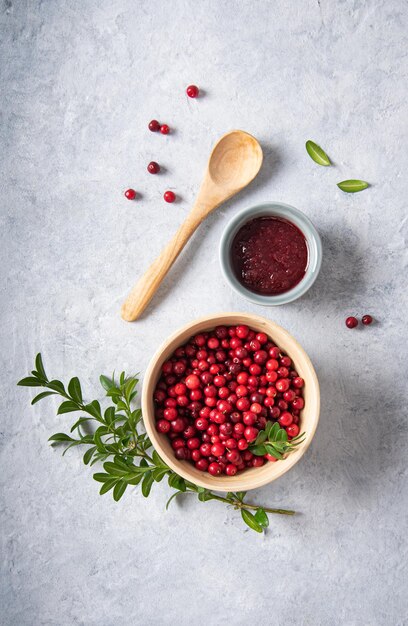 Arándano rojo del bosque jugoso con mermelada hecha a mano en un tazón de madera sobre una mesa blanca Concepto de comida saludable casera Vista superior e imagen del espacio de copia