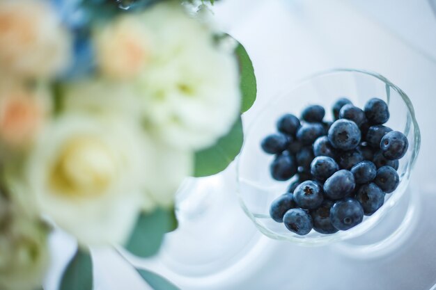 arándano en vidrio y flores blancas y azules en la decoración de la boda