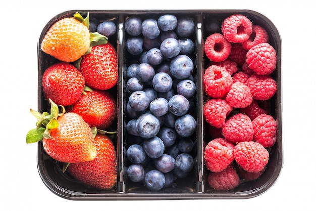 Arándanos, fresas y frambuesas en una caja aislada o