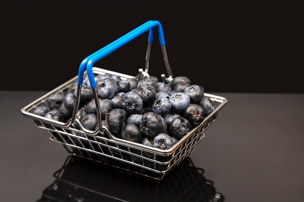 Arándanos frescos en una cesta de la compra sobre un fondo con una imagen de espejo. alimentos vitamínicos para la salud