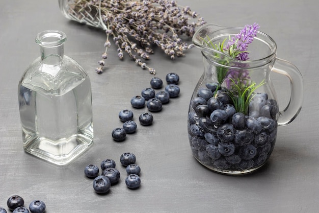 Arándanos en una jarra de cristal con agua Botella de agua Lavanda y arándanos sobre la mesa