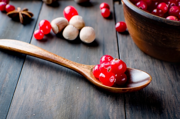 Arándanos jugosos en una cuchara de madera y especias en la mesa de madera