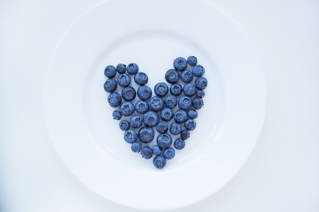 Arándanos maduros en forma de corazón en un plato blanco